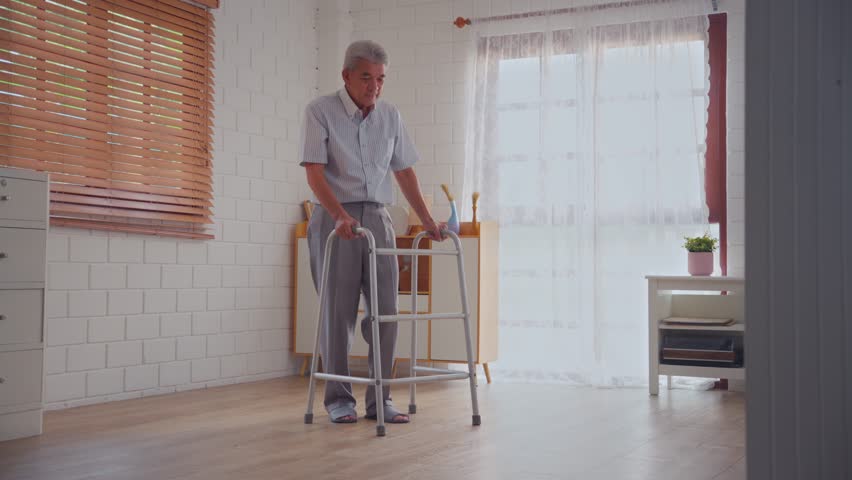 Asian caregiver helping senior male from falling on the ground at home. Elderly older patient having an accident after doing physical therapy then rescued by attractive therapist nurse in living room. Royalty-Free Stock Footage #3394135869