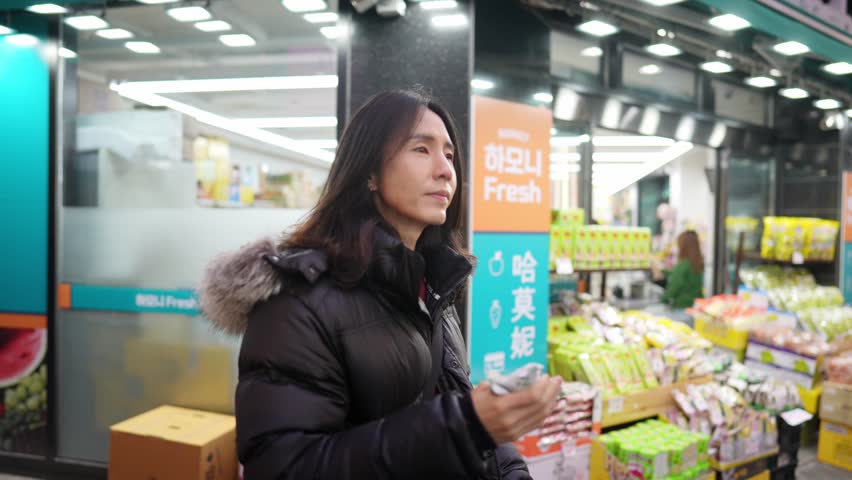 A South Korean man in his 30s with long hair, sightseeing in the winter snowfall on a street in Myeongdong, Seoul, South Korea.