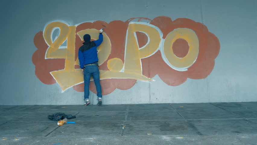 Graffiti. A young guy draws on the wall.