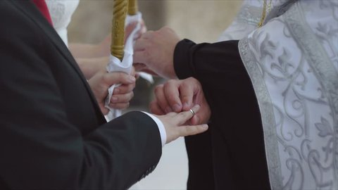 Closeup Orthodox priest performing rite of exchanging rings for marrying