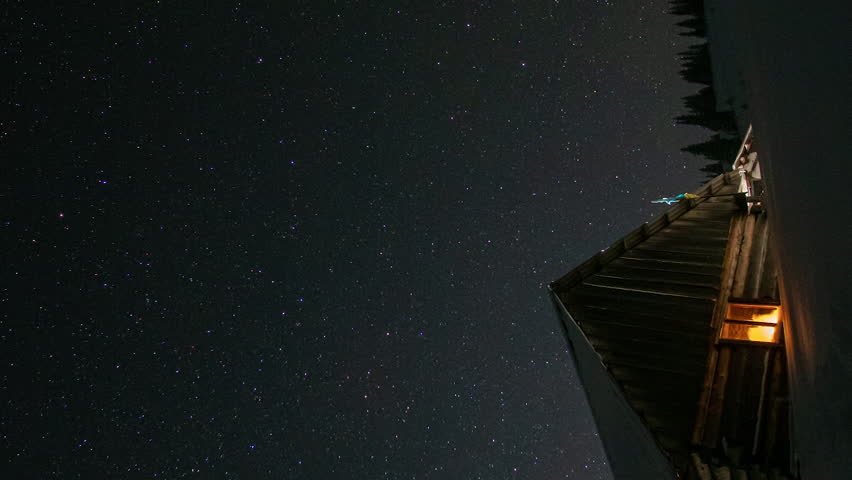 Time lapse of Star trails in the night sky, Wooden house in the mountains in winter, Stars move around a polar star. vertical footage