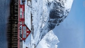 Timelapse of traditional fishing village A on Lofoten Islands, Norway with red rorbu houses. With snow in winter. Camera panning