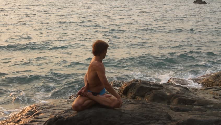 HD: Yoga man doing exercise on the deserted wild stone sea beach.