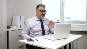 A middle-aged man communicates via video conference. He smiles widely and nods welcomingly. The video is suitable for content about office work, remote work and remote communication via the Internet.