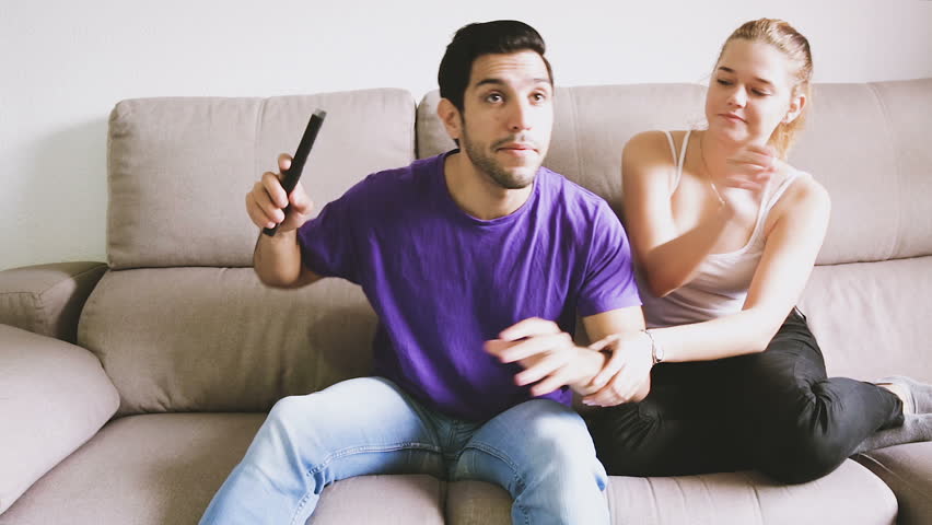 Young upset woman trying to take away TV remote from her boyfriend Royalty-Free Stock Footage #33945253