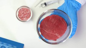 Hands of scientific researcher holding a sample of cultured meat in petri dish, cultivated meat, cellular agriculture, synthetic meat innovation concept flat lay video