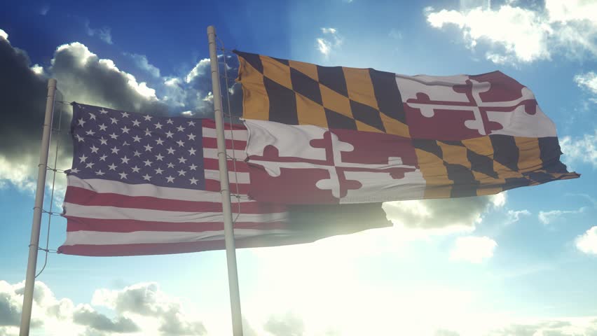 The Maryland state flags waving along with the national flag of the United States of America. In the background there is a clear sky