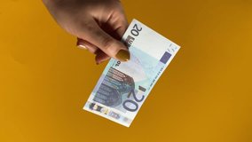 Paper money collapse, replacing currency, finance concept. A female hand holds a banknote, igniting Euro note as it gracefully burns indoors. Vertical video isolated on yellow or orange background