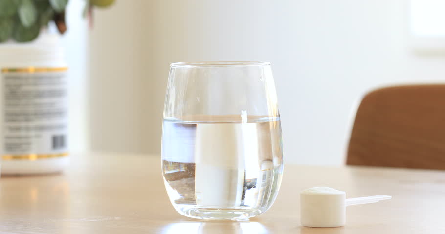 Collagen powder is poured into a glass of water and stirred with a spoon. Health