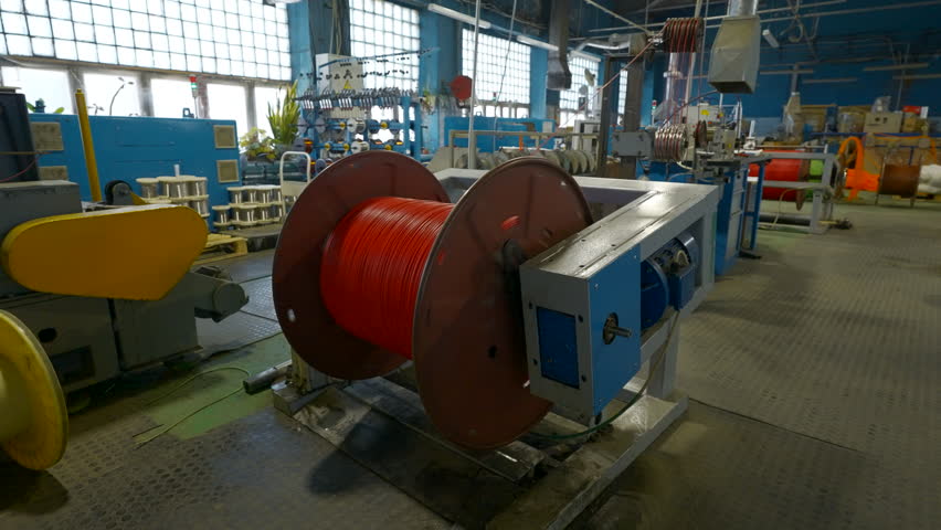 Rotating coil with wires in factory. Creative. Winding cable on to coil on production machine. Process of winding cables at metallurgical plant