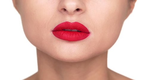 Extreme close up portrait of irritated female person twisting her lips covered with red matte lipstick being nervous over white background. Facial expressions