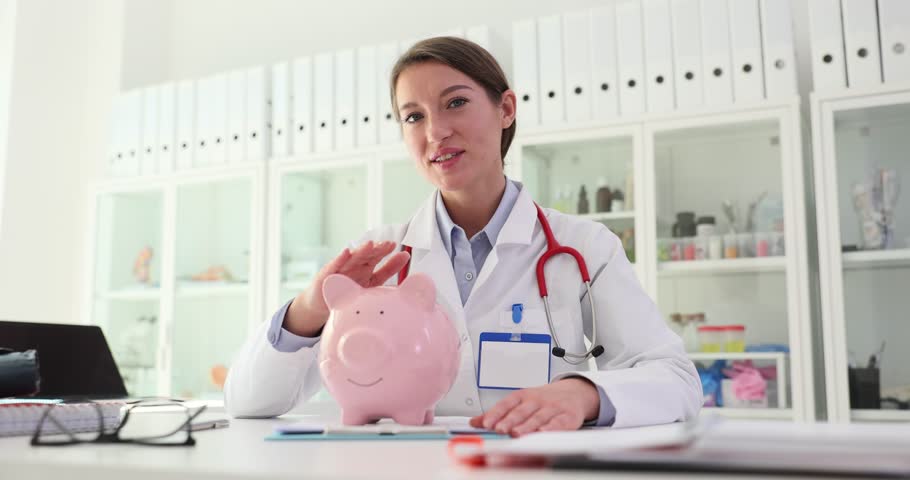 Female doctor holds and strokes piggy bank in clinic. Medical insurance and healthcare budget Royalty-Free Stock Footage #3394924221