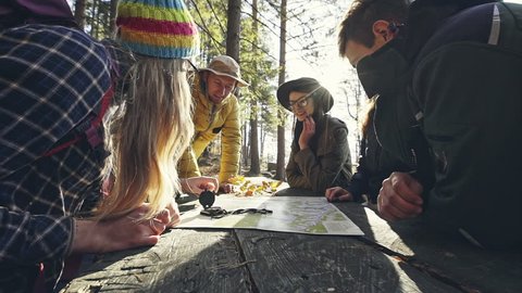 Group of friends discussing over map in forest