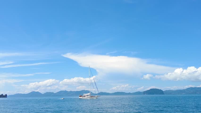 A large sailing yacht passes in the distance against the backdrop of Krabi province, yachting in Thailand, yachting in the tropics