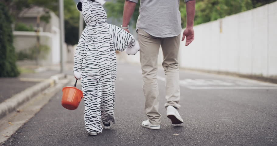 Halloween, trick or treat with child and father walking in street, holding hands or animal costume on holiday. Dad, kid and lantern basket for candy or sweets in fun neighborhood dress up celebration