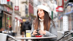 French style woman smiling looking away sitting in an outdoor cafeteria