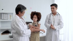 Two specialist doctor in medicine providing health care services consultation treatment in hospital to little kid. Doctors talking with kid in the hospital meeting room.