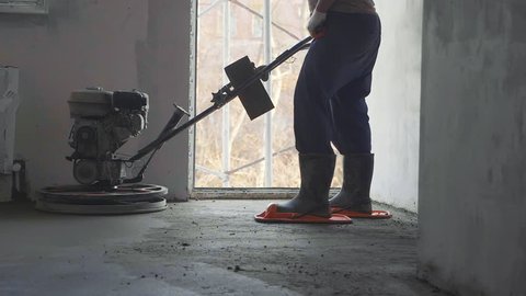 Builder polishing mortar floor at construction site of new appartments. Mechanized grout screed concrete floor close-up slow motion