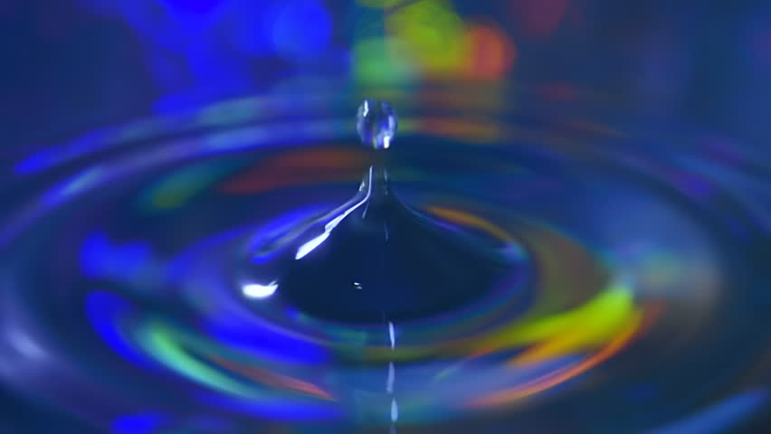 Water drop falls on the colorful surface of the water and flies upwards. Macro. Closeup. Shallow depth of field. Slow mo, slo mo, slow motion, high speed camera, 240fps, 250fps