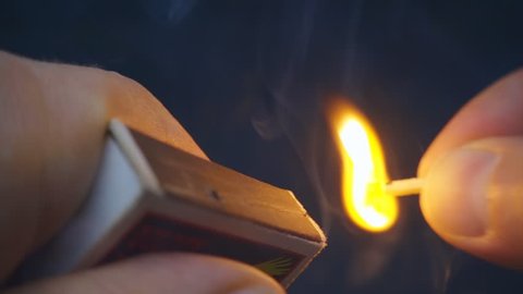 The match in the hand moves on the side of the matchbox and light the fire. S-log - High Dynamic Range. Macro. Closeup. Shallow depth of field. Slow mo, slo mo, slow motion, high speed camera, 240fps,