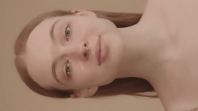 Young attractive woman gently massaging face. Prevention of facial skin aging and wrinkles. Portrait of Caucasian woman shows face skin care. Slow motion. Daily beauty routine 12 vertical videos