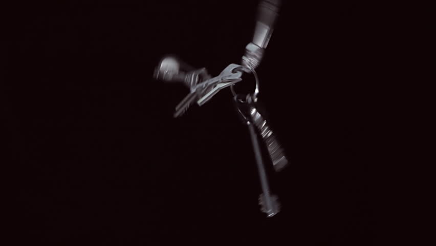 A bunch of shiny keys from the apartment, at home flies and rotates on a black background. Closeup. Slow mo, slo mo, slow motion, high speed camera, 240fps, 250fps