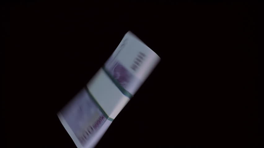 A pack of hundred-euro bills flies and rotates on a black background. Closeup. Slow mo, slo mo, slow motion, high speed camera, 240fps, 250fps