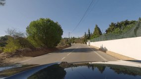 First person view, FPV, from dashcam of car driving towards the Benagil Caves, Algarve Coast, Portugal. Road trip video in POV, with blue sky on a bright sunny day, driving on narrow roads