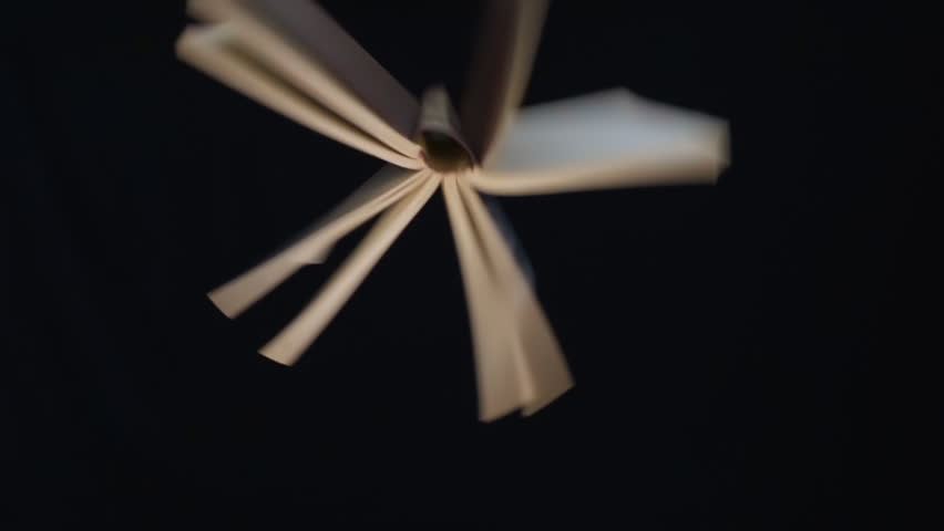 The book fall, rotate on a black background and the pages evolve in the air. Closeup. Slow mo, slo mo, slow motion, high speed camera, 240fps, 250fps