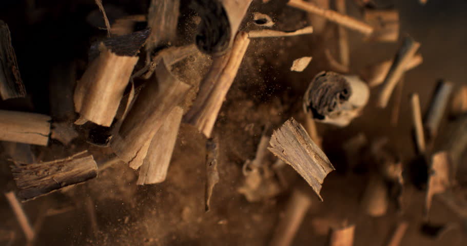 Super slow motion macro of bio organic cinnamon sticks are flying with cinnamon powder particles explosion at 1000 fps isolated on black background.