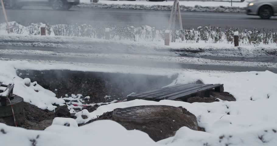 Steam coming out of the ground in an urban residential district, winter snow, cold. Urban street, accident hot water sewer pipeline, hot steam comes out of pit clouds, the water boils. Royalty-Free Stock Footage #3395274507
