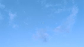 video of the moon during the day with a blue sky background