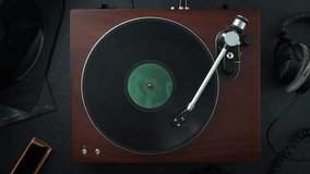 Wooden Record Player with the Tonearm Lowered onto a Vinyl Spinning in Slow Motion - Top View of the Audiophile's Table - Powered by Shutterstock - Get 15% off with code: PIKWIZARD15