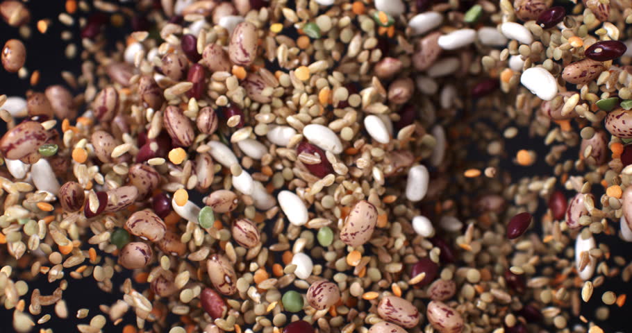 Super slow motion macro of pile dry quality legumes and cereals mix explosion with flying grains on isolated on black background at 1000 fps.