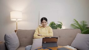 Young asian woman watching music video on digital tablet
