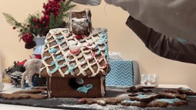 Little boy decorates gingerbread house with icing, Christmas mood. New Year or Christmas video. Children's educational game and cooking classes.