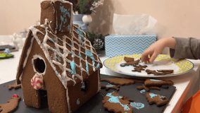 Little boy decorates gingerbread house with icing, Christmas mood. New Year or Christmas video. Children's educational game and cooking classes.