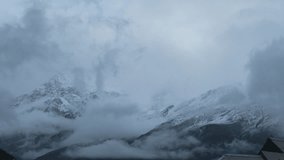 4K shot of storm clouds rolling over snow covered mountains in Keylong, India. Snow storm during winter in Indian Himalayas. Time-lapse footage of earth landscape with moving clouds.