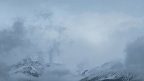 4k shot of dark storm clouds on snow covered mountains during winter season in Lahaul, India. Snow storm on mountains. Himalayas mountain landscape. Mountains and clouds time lapse.