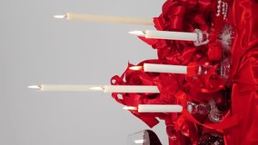 Candle composition on candlestick with red ribbons. Vertical footage. Burning candles on white background. Valentine's Day decoration. romance festive atmosphere. 4 k video