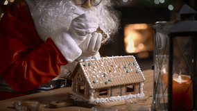 Santa Claus decorating a gingerbread house with sweet patterns in his residence with a fireplace and a Christmas tree - Powered by Shutterstock - Get 15% off with code: PIKWIZARD15