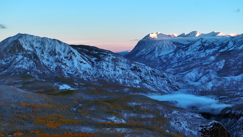 First light Kebler Pass Crested Butte Gunnison Colorado seasons crash aerial drone early fall aspen tree red yellow orange forest winter first snow cold sunrise clouds Rocky Mountain peak back motion