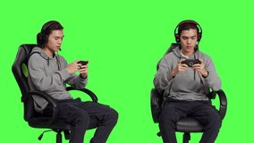 Over greenscreen, asian teenager enjoys mobile video games holding smartphone and participating in online multiplayer contest. Gamer uses phone to engage in new roleplaying activity.