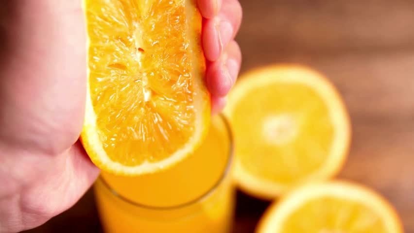 Squeezing out the fresh orange. A picture of a person's hand squeezing orange juice. Hand squeezing half fresh oranges on the orange press with pulp. hand holding fresh raw citrus. Royalty-Free Stock Footage #3395781305