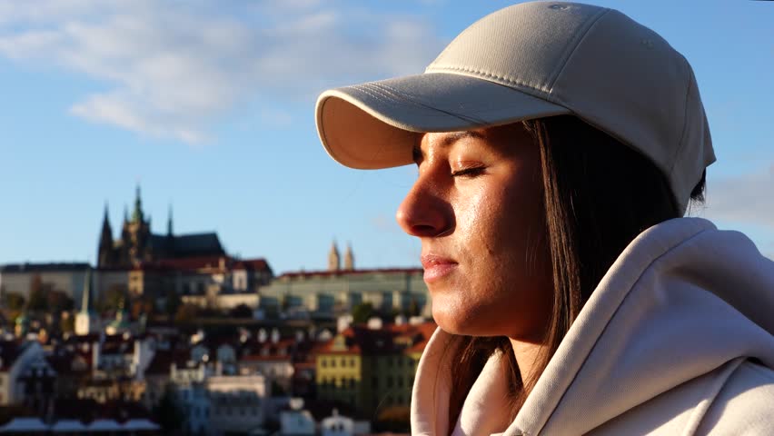 Girl peacefully stand and open eyes enjoying Prague city during golden hour