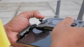 Close up of a man's hand holding a modern drone controller, outdoors.