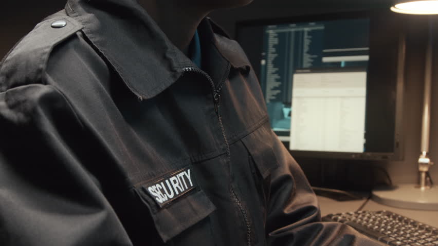 Tilt cropped shot of unrecognizable African American female security officer using handheld transceiver while controlling CCTV video footages on multiple monitors in guard room Royalty-Free Stock Footage #3395811391