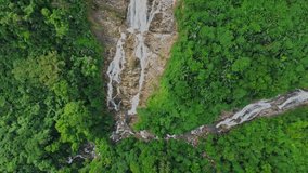 Water flowing down from a waterfall on a high cliff in the jungle, aerial view from drone.  Epic cinematic.