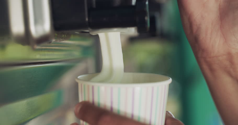 Person, hands and ice cream swirl with machine for sweet desert, sundae or food in a cup. Closeup of vanilla serving frozen yoghurt, creme or milky soft serve in tub for summer treat at dairy cafe