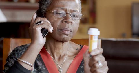 Happy black senior woman refilling her prescription to a pharmacy or talking to her doctor about her health care on a cordless phone